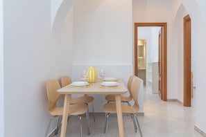 A dining area with a table set for four, chairs, and a decorative vase. - Mary & Jo's Apartments (Naxos)