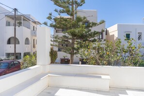 A residential building with a white facade, balconies, and a tree in the foreground. - Mary & Jo's Apartments (Naxos)