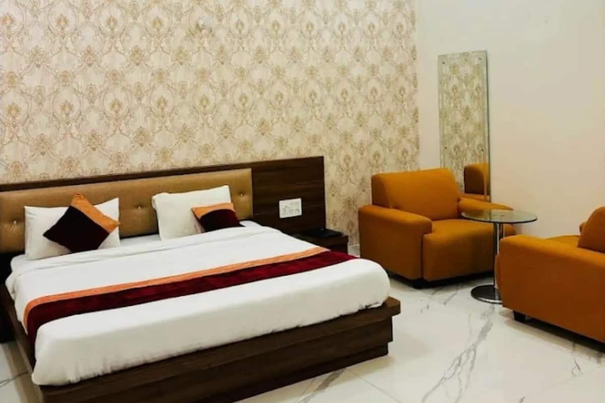 Ein Hotelzimmer mit einem großen Bett, zwei Sesseln, einem kleinen Tisch und einem Spiegel an der Wand.