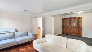 A living room with a light grey sofa, a white sofa, and a wooden cabinet. - Metawise Spacious 4-bedroom Home in Cherrybrook (Sydney)