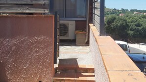 A building with a sign indicating a general renovation enterprise, a window, and a staircase leading to an air conditioning unit. - 2-bedroom apartment with terrace 5 minutes from the center and beaches (Collioure)