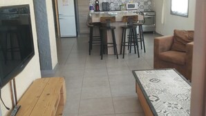 A modern living room with a TV, wooden bench, and a patterned coffee table. - 2-bedroom apartment with terrace 5 minutes from the center and beaches (Collioure)