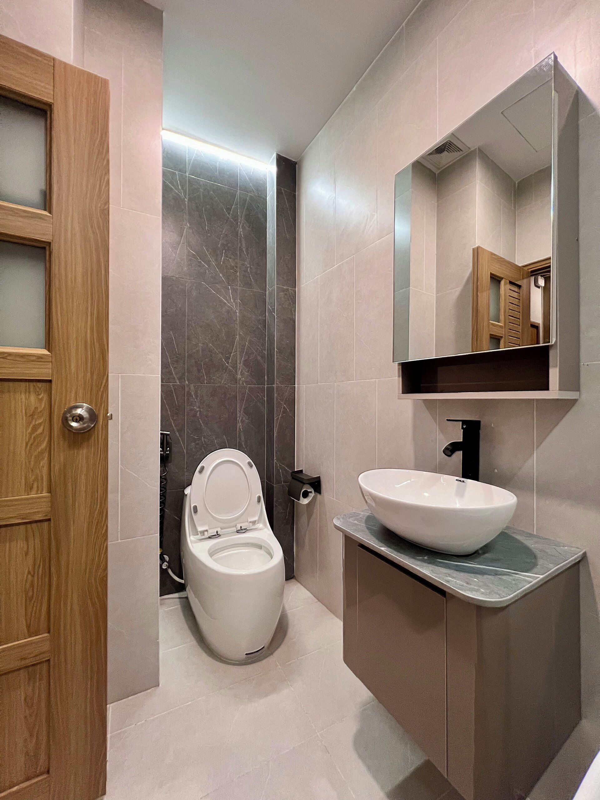 Ein modernes Badezimmer mit Toilette, Waschbecken und Spiegel.