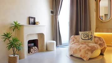 Una sala de estar con chimenea, una planta en maceta, un sillón mullido y un tapete redondo.