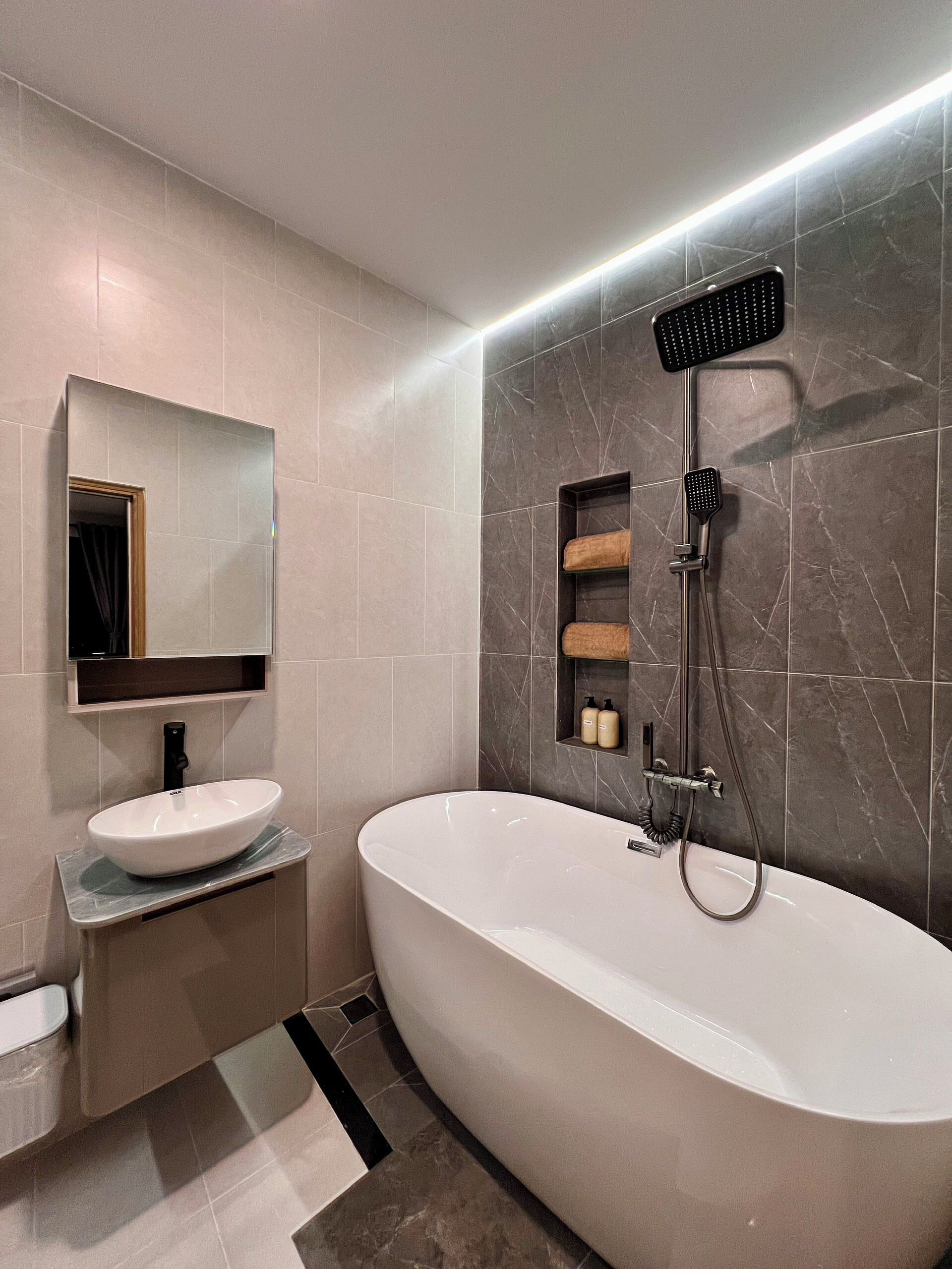 A modern bathroom with a freestanding bathtub, a wall-mounted showerhead, and a vanity with a sink and mirror.