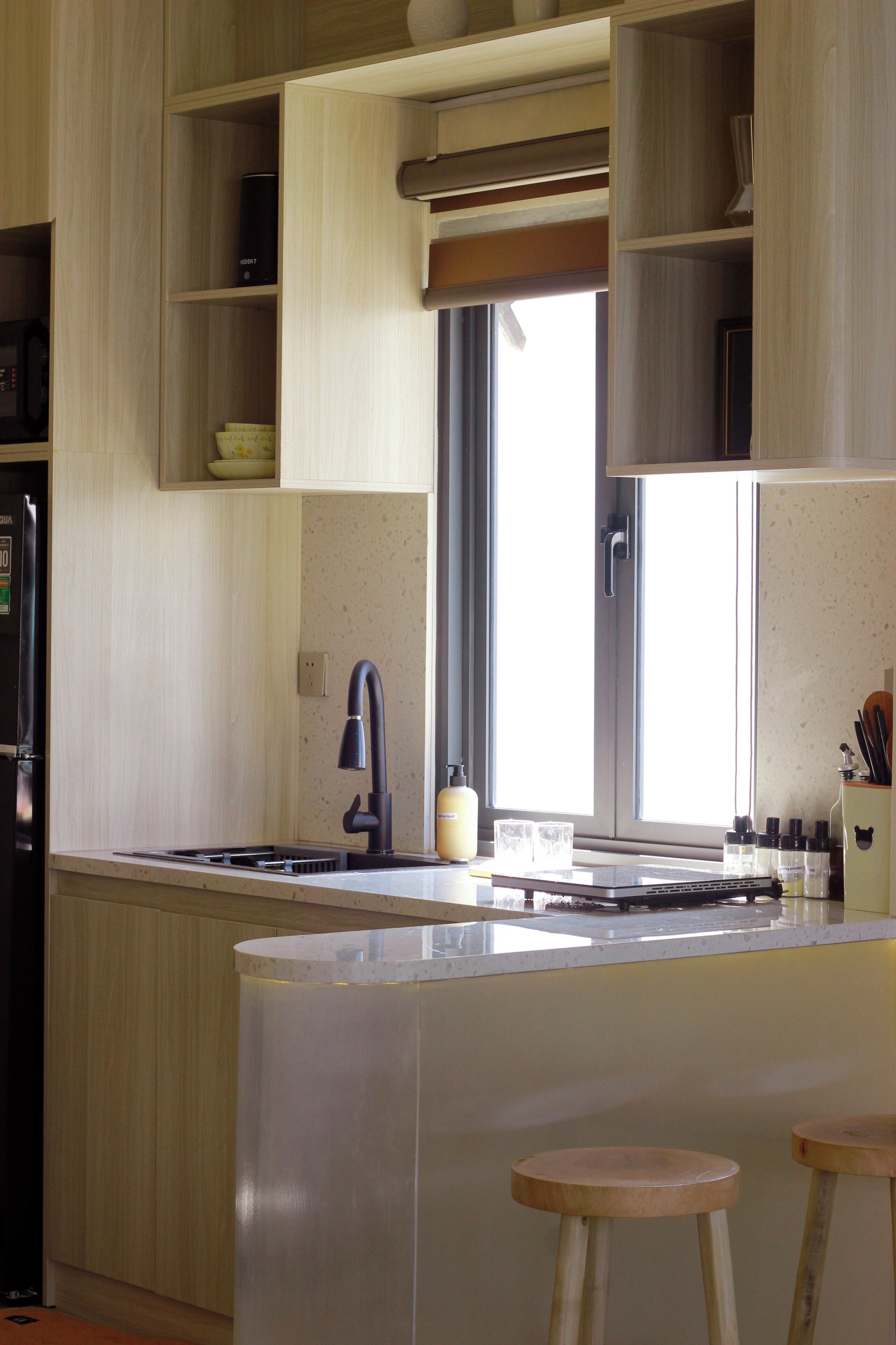 Una cocina moderna con una isla central, un lavamanos empotrado y taburetes de madera.