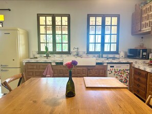 A kitchen with wooden cabinets, a refrigerator, a microwave, and a window with a view of greenery. - The house - ideal for families, with plenty to keep young and old entertained! (Mimet)