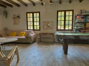 A cozy room with a wooden floor, a pink sofa, a small table, and a pool table. - The house - ideal for families, with plenty to keep young and old entertained! (Mimet)