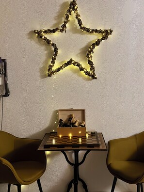 A room with a star-shaped light fixture, a chessboard on a table, and two chairs. - The house - ideal for families, with plenty to keep young and old entertained! (Mimet)