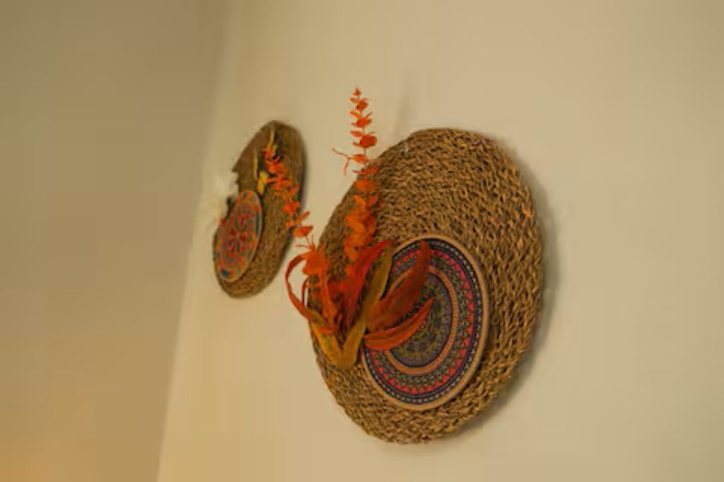 Two woven baskets with decorative patterns and orange accents, hanging on a plain wall.