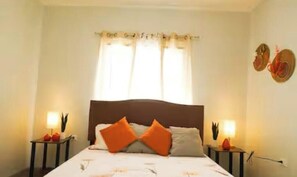 Ein Schlafzimmer mit einem Bett, zwei Nachttischen, einem Fenster mit Vorhängen und Wandbildern.