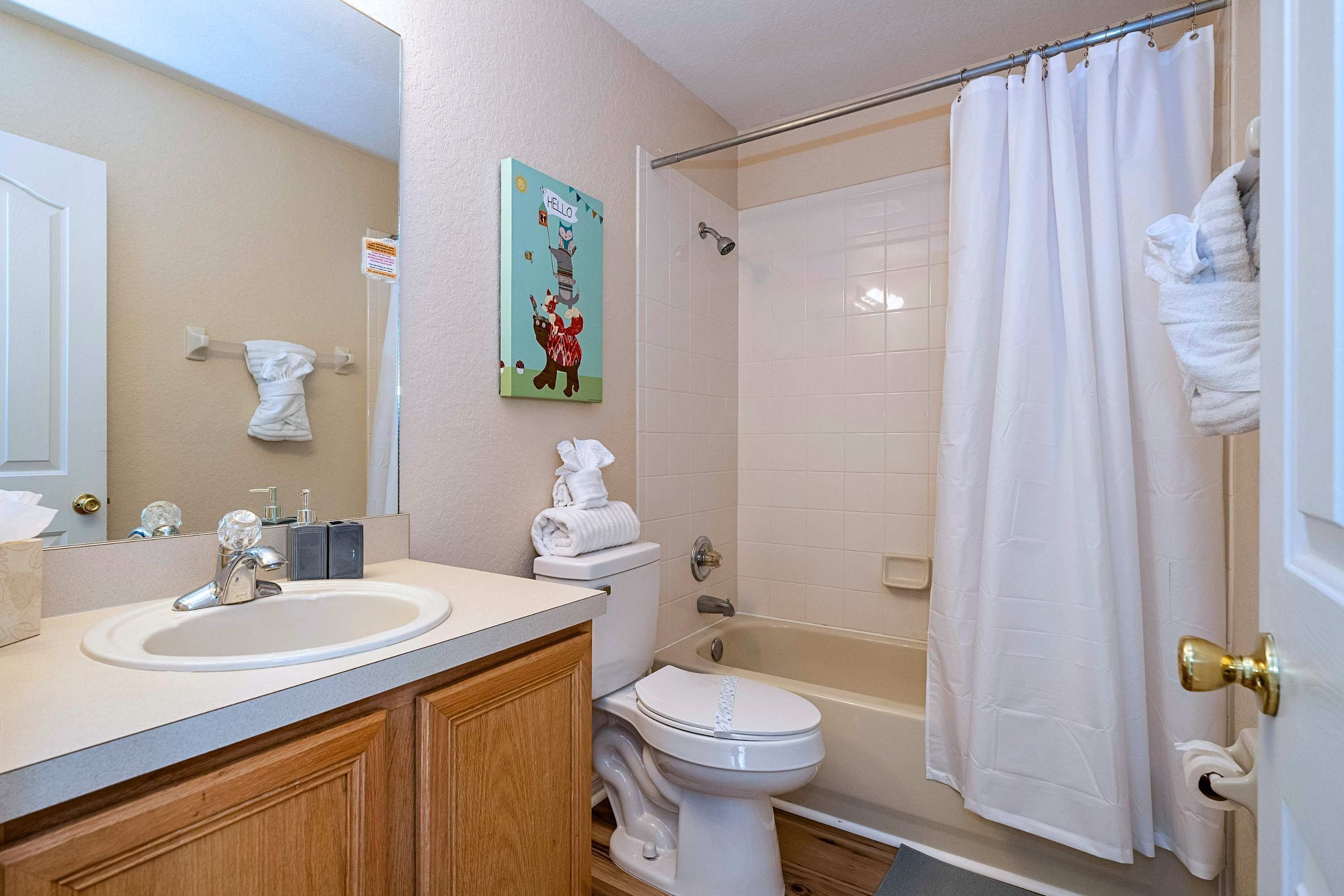A bathroom with a sink, toilet, and bathtub, featuring a shower curtain and a towel rack.