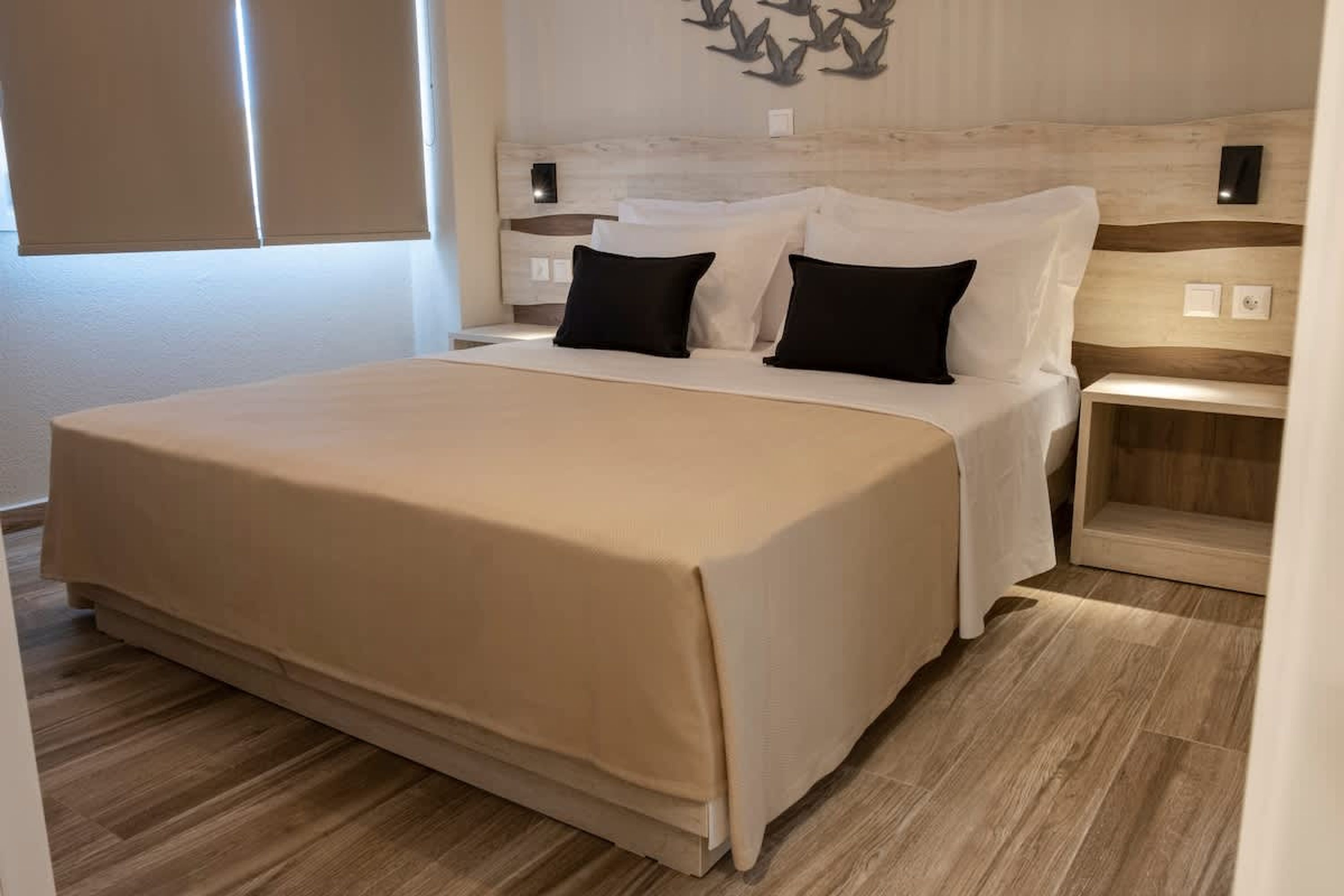 Une chambre à coucher comprenant un lit, des tables de chevet et un luminaire fixé au mur.
