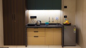 A compact kitchen with a built-in coffee maker, a kettle, and a refrigerator.