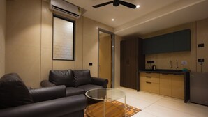 A modern living room with a leather sofa, a glass coffee table, and a ceiling fan.