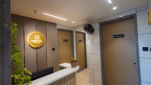 A reception area with a modern design, including a reception desk, a sign for 'Nirritul The North Way,' and a sign for 'Nirritul Sapphire.' - Nirrtul Crystal 1BHK Apartment Cozy & Quite (Surat)