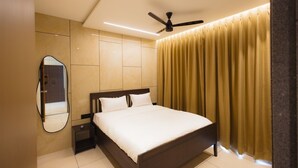 A bedroom with a bed, a ceiling fan, a nightstand, a mirror, and a curtain. - Nirrtul Crystal 1BHK Apartment Cozy & Quite (Surat)