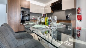 Une cuisine moderne avec un coin repas, équipée d’un four à micro-ondes, d’un four et d’un téléviseur à écran plat.