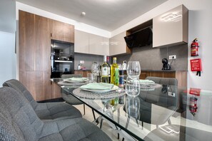 Eine moderne Küche mit Essbereich, ausgestattet mit Mikrowelle, Backofen und einem Flachbildfernseher.