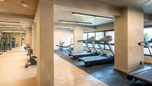 A gym with treadmills, weight machines, and a mirrored wall. - Studio charmoso e bem localizado (São Paulo)