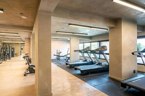 Ein Fitnessstudio mit Laufbändern, Kraftgeräten und einer Spiegelwand.