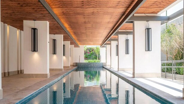 A long indoor swimming pool with a wooden ceiling and white walls. - Studio charmoso e bem localizado (São Paulo)