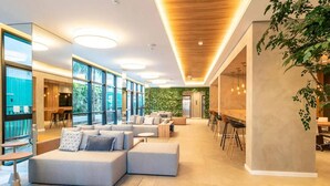 A modern interior with a seating area, large windows, and a green wall. - Studio charmoso e bem localizado (São Paulo)