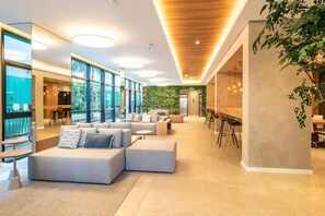 Ein modernes Interieur mit einer Sitzecke, großen Fenstern und einer grünen Wand.