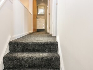 A carpeted staircase leading to a bathroom with a mirror and a sink. - The Old School (Peebles)