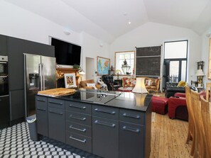 Una cocina moderna con una isla central, horno empotrado y un refrigerador grande.