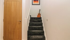 Una puerta de madera, una escalera con peldaños alfombrados y un cuadro enmarcado en la pared.