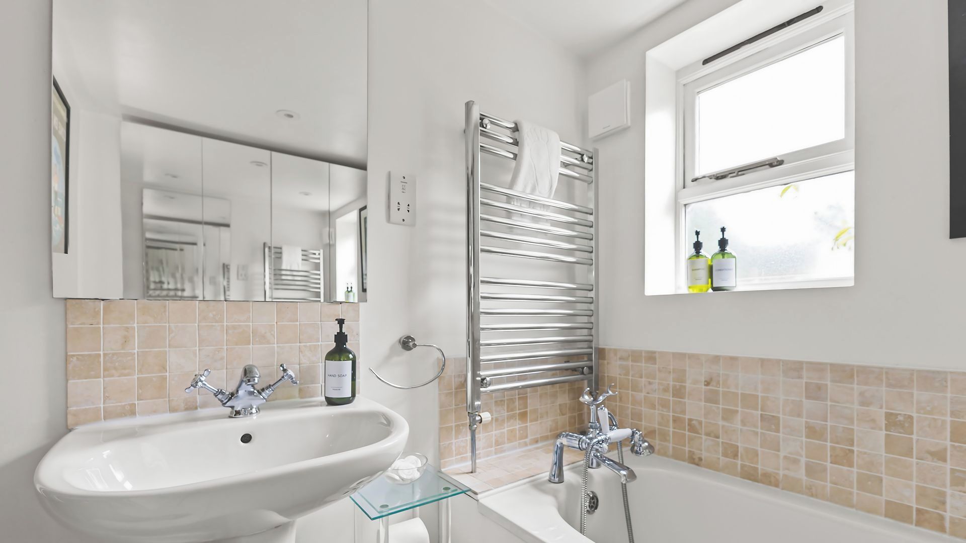 A modern bathroom with a large sink, a glass-topped vanity, a bathtub, and a towel rack.