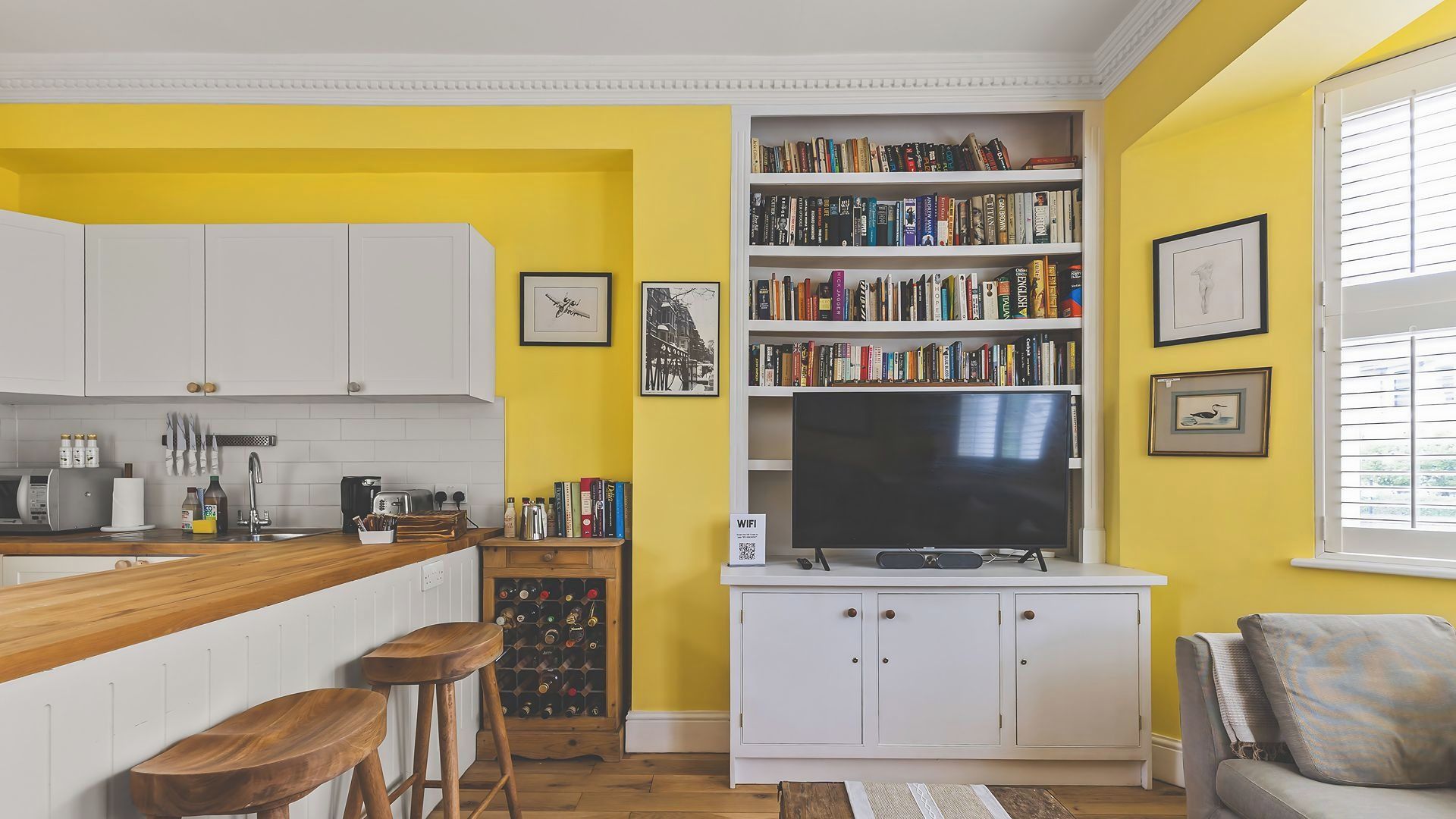 A kitchen with white cabinets, a wooden countertop, and a built-in TV shelf.