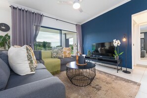A modern living room with a sofa, TV, and decorative items. - Ballito Village Estate (Ballito)