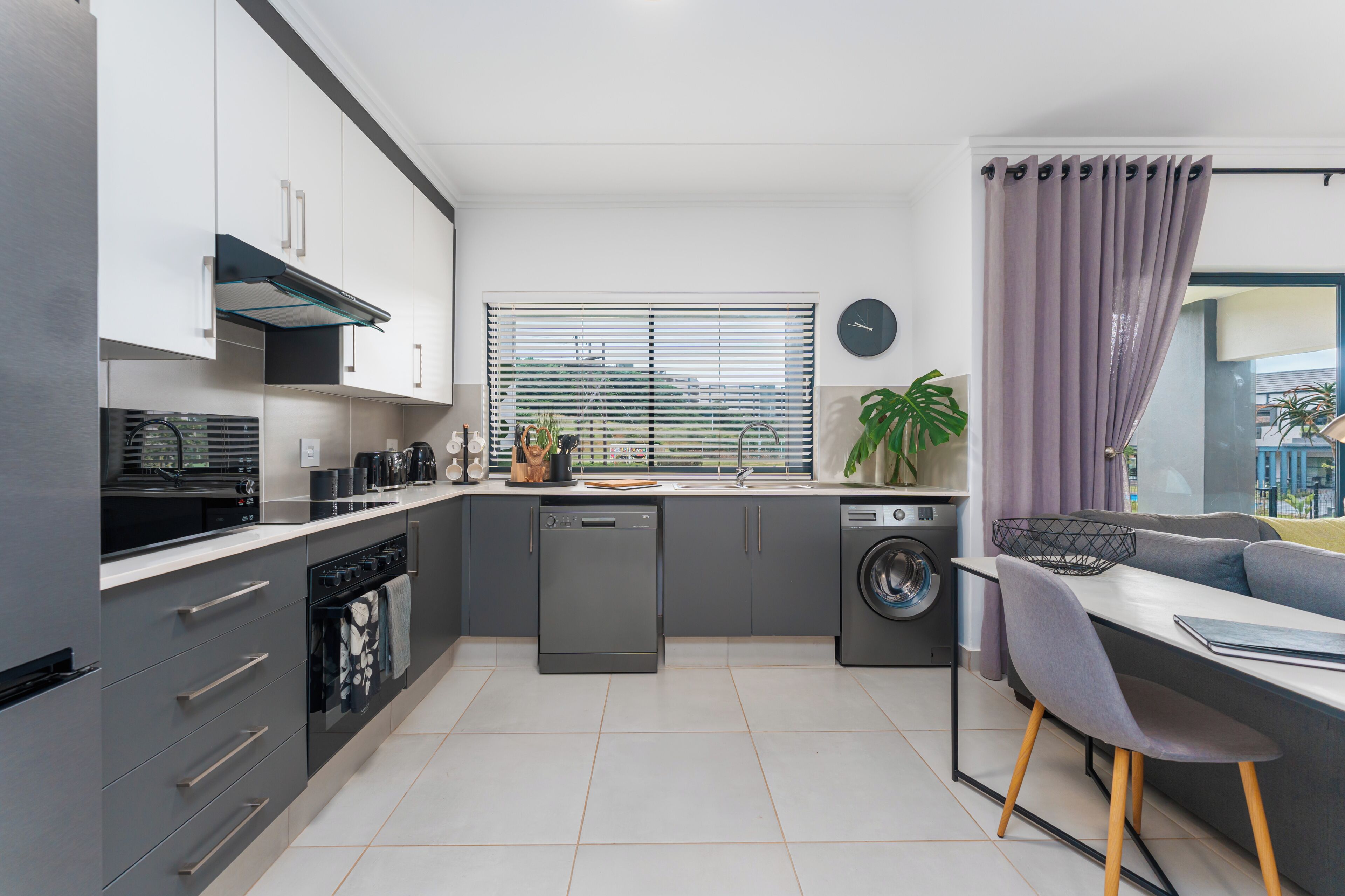 Een moderne keuken met inbouwapparatuur, een eethoek met een bank, en uitzicht door het raam.