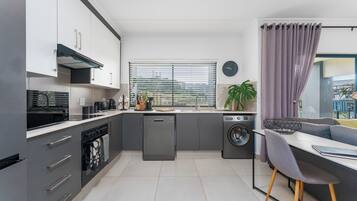 Een moderne keuken met inbouwapparatuur, een eethoek met een bank, en uitzicht door het raam.