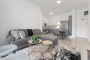 A modern living room with a grey sofa, two round coffee tables, and a black and white rug. - Ballito Village Estate (Ballito)