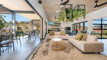 A spacious indoor area with a sofa, chairs, a round wicker table, and hanging plants.