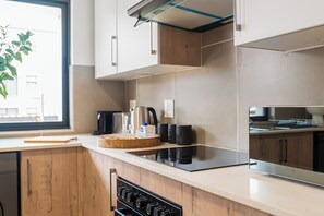 A modern kitchen with a built-in oven, a coffee maker, and a kettle on the counter. - Ballito Village Estate (Ballito)