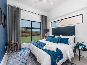A bedroom with a large bed, a view of a tennis court, and a modern design.