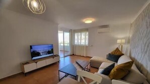 A living room with a television, a sofa, a coffee table, and a dining table. - El Rincon 11 - One Bed (Los Cristianos)