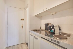 Eine Küche mit weißen Schränken, einer Edelstahl-Spüle, einer Kaffeemaschine und einem Herd.
