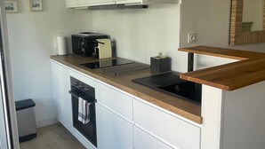 Una cocina moderna con armarios blancos, encimera de madera, horno empotrado y microondas.