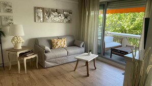 Un salón con sofá, una mesita, una lámpara y vistas al exterior con vegetación.