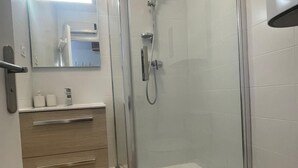 Un baño moderno con ducha de vidrio, tocador de madera y váter blanco.