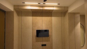 Moderni kylpyhuone, jossa on seinälle asennettu litteänäyttöinen televisio, upotetut valaisimet ja minimalistinen muotoilu.
