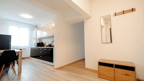 A modern kitchen with white cabinets, a black countertop, and a wooden dining table with chairs.