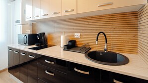 A modern kitchen with a sink, countertop, and wooden panel backsplash.