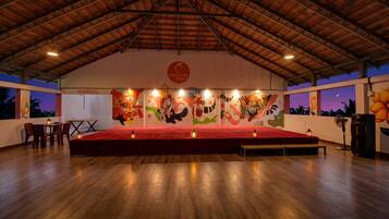 Un espacio interior con un escenario, asientos y obras de arte en las paredes.