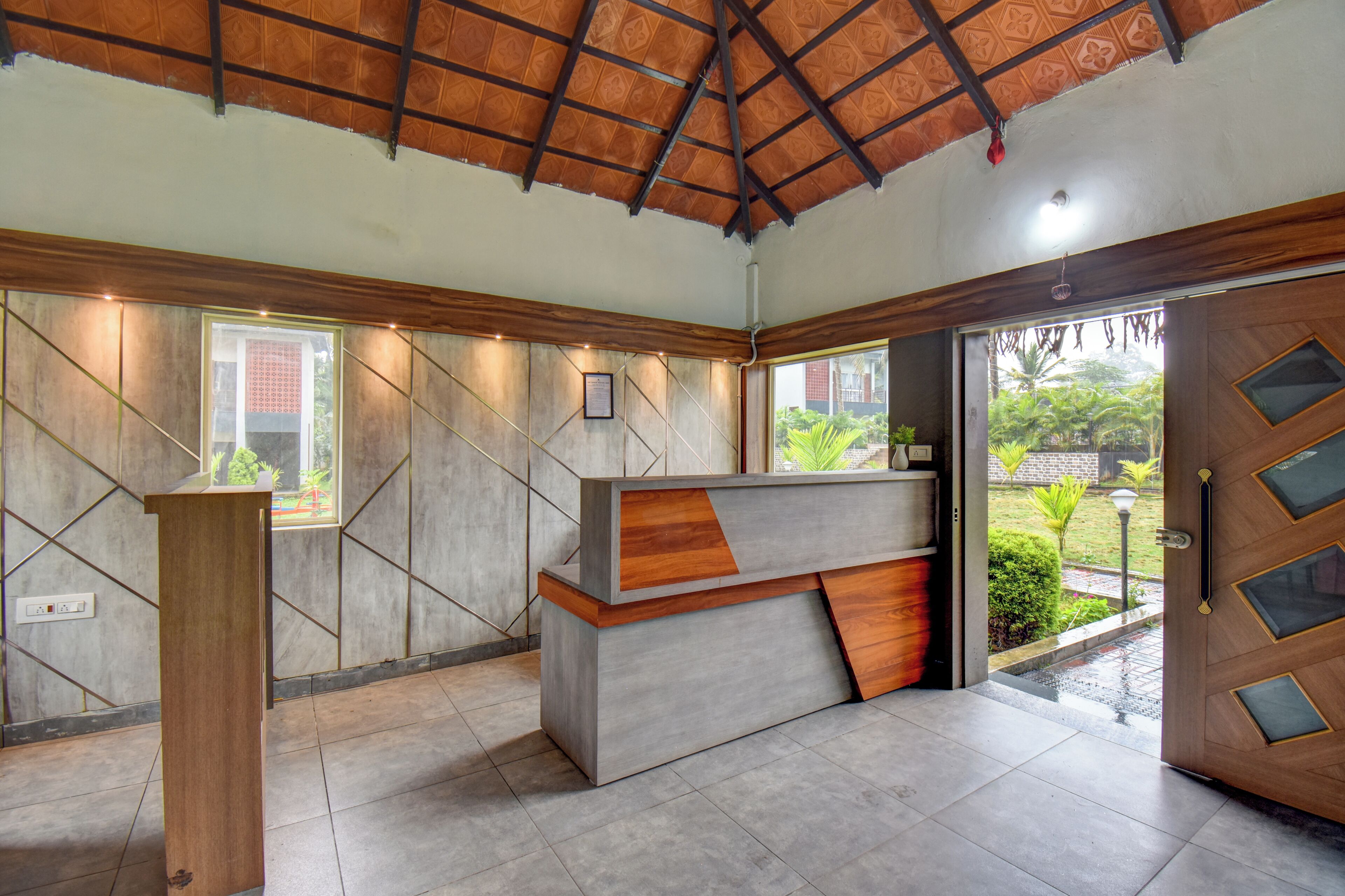Un mostrador de recepción con detalles de madera, piso de baldosas y techo con diseño decorativo.